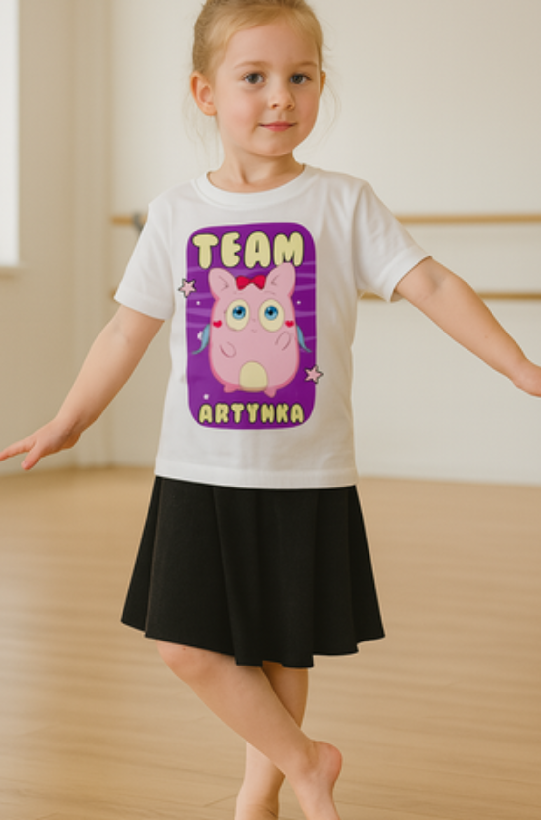 Biały tshirt dziecięcy z różową postacia artynki z napisem. uszyty z dobrej bawełny, prezentowany na modelce. Nadruk na przodzie