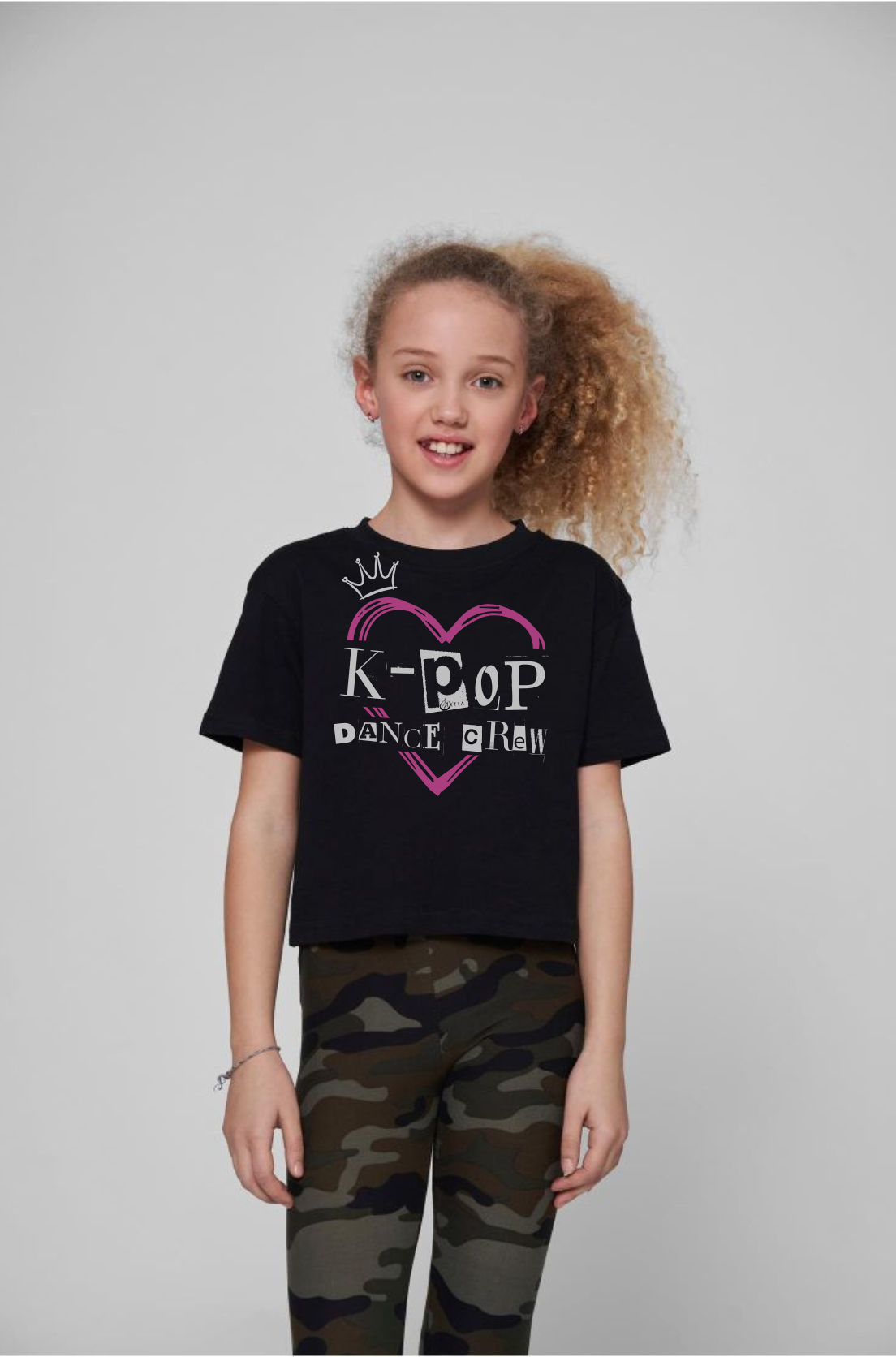 Czarny tshirt dziecięcy z białym napisem kpop crew wkoponowanym w rózowe serce. uszyty z dobrej bawełny, prezentowany na modelce. Nadruk na przodzie